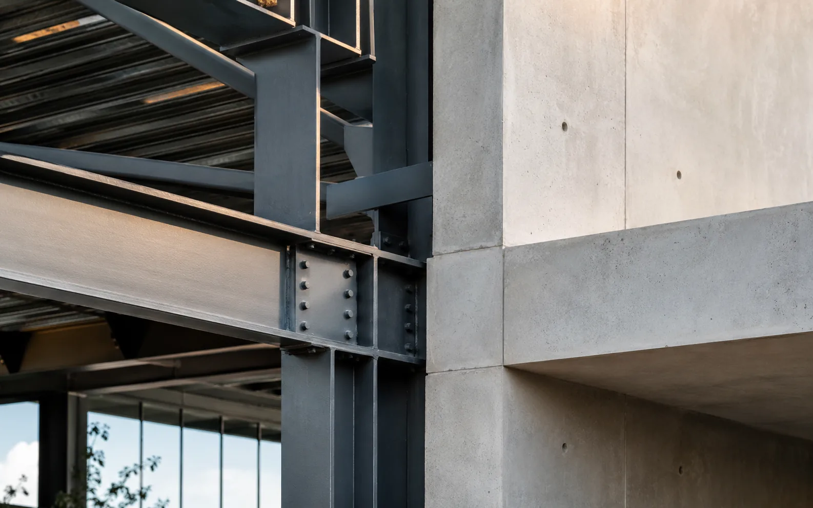 Structural detail of an exposed concrete frame meeting a timber screen